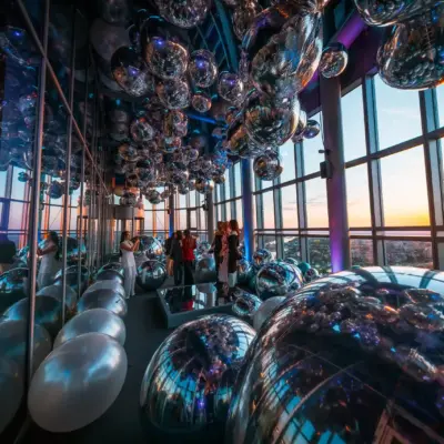 Guests at the Belgrade 360 Deck VIP opening surrounded by silver balloons with a panoramic view of the Belgrade sunset.